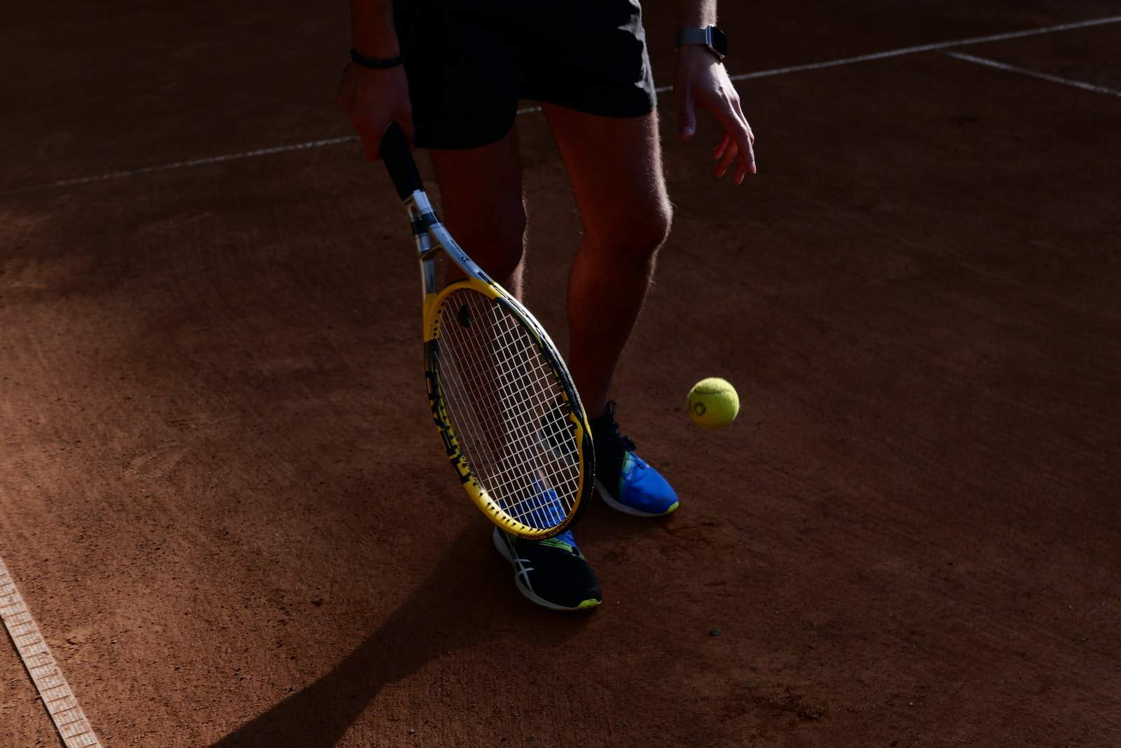 person in black shorts holding yellow tennis racket